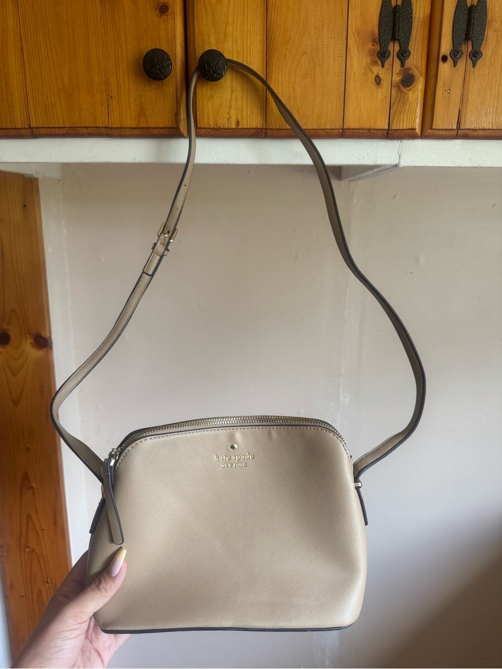 kate spade cream crossbody with adjustable strap and gold logo